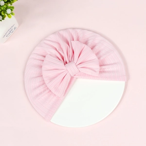 Close-up of pink ribbed baby beanie featuring a large decorative bow and soft texture