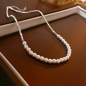 Gros plan d'un collier de perles argentées posé sur un écrin à bijoux marron