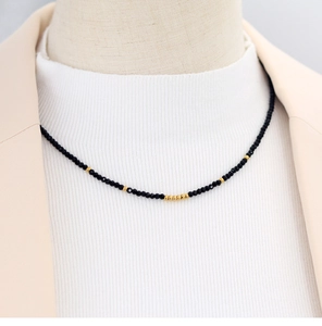 Macro shot of faceted black beads and gold accents on a minimalist collar necklace