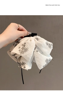 Détail de la pince à cheveux en mousseline blanche avec broderie florale noire élégante
