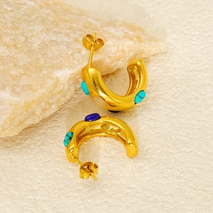 Detail of chunky gold C-shaped earrings inlaid with turquoise and multicolor stones