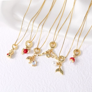Gold-plated necklaces featuring delicate heart, mermaid tail, and shell charms on white fabric