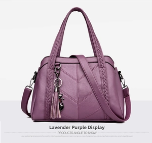 Detail of lavender purple faux leather handbag with V-shaped stitching and tassel cat charm