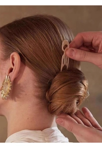 Close-up of a minimalist beige U-shaped hair pin used on a bun for an elegant hairstyle