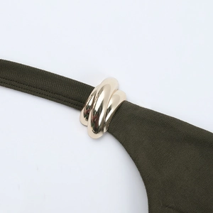 Détail d'une robe en maille vert foncé avec une boucle métallique dorée élégante