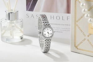 Detail of square silver quartz watch featuring rhinestone bezel and Roman numerals