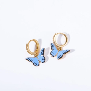 Détail macro de boucles d'oreilles papillon dorées avec émail bleu et oxydes de zirconium