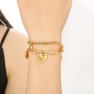 Detail of 18K gold-plated double-layer heart bracelet with Cuban and oval links on wrist