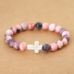 Close-up of beaded bracelet featuring marble texture stones and a white cross pendant