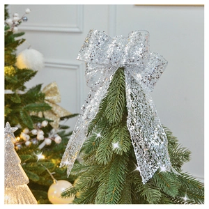 Detail of silver sequin lace bow topper on Christmas tree with warm blurry lights