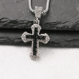 Dettaglio di un ciondolo a croce in argento con pietre nere e cristalli micro-pavé