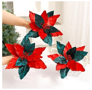 Detail of red and green velvet Christmas poinsettia flowers with gold glitter accents