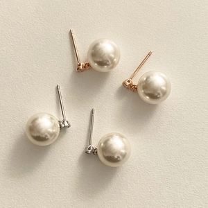Detailed view of sterling silver pearl stud earrings in gold and silver finish on fabric