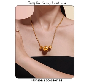 Close-up of golden double-layer necklace featuring three spherical beads on a snake chain
