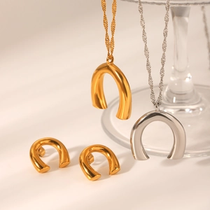 Detail of high-polish U-shaped pendant necklace and horseshoe stud earrings jewelry set