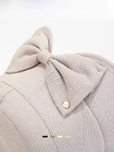 Close-up of knit bucket hat featuring large bow detail and gold metal saga button