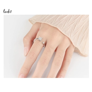 Close-up of adjustable silver spinning ring with star-shaped zircon on a finger