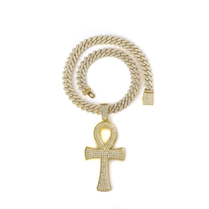 Détail macro du pendentif Ankh doré orné de cristaux sur une chaîne cubaine de style hip-hop