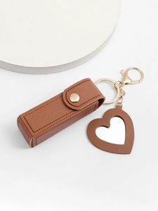 Close-up of brown PU leather lipstick case and heart-shaped mirror on gold keychain