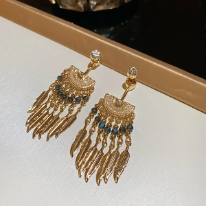 Macro detail of French vintage gold earrings featuring blue beads and feather pendants