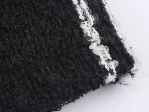 Close-up detail of black bouclé knit fabric with contrasting white vertical stripe texture