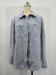 Detail of light blue washed denim jacket featuring classic collar and symmetrical chest pockets