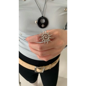 Close-up of oversized silver sunburst ring with spiral texture on a finger