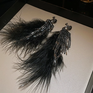 Detail of dark gothic tassel clip-on earrings with black feathers and beads