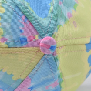 Macro detail of multi-color camouflage baseball cap with pink stitching and top button
