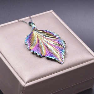 Macro shot of colorful iridescent stainless steel leaf pendant on luxury satin box