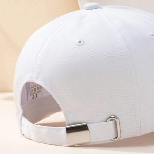 Close-up of white cotton baseball cap with adjustable silver metal buckle and neat stitching