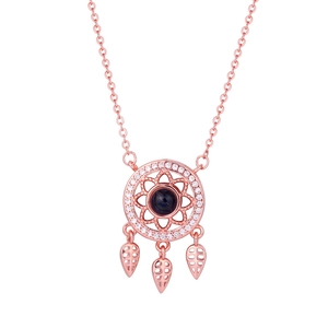 Rose gold dreamcatcher necklace with blue projection stone and leaf charms on white background