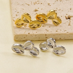 Close-up of minimalist gold and silver leaf-shaped stud earrings with textured finish
