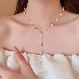 Dettaglio della collana a Y placcata oro 18k con perle irregolari e perline dorate sul collo