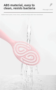Pink massage hairbrush with hollow back design being rinsed under running water for easy cleaning