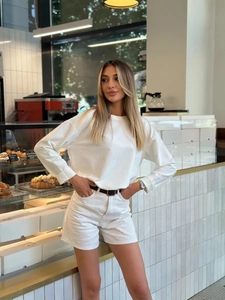 Dettaglio di maglietta in cotone a maniche lunghe e pantaloncini in denim bianco con cintura