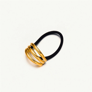 Close-up of golden metal triple-ring ornament on a black elastic hair tie