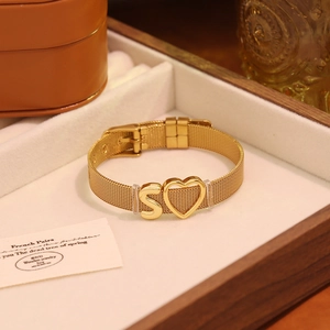 Détail d'un bracelet en maille dorée avec lettre S et breloque coeur en écrin cadeau