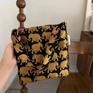 Gros plan détaillé du sac en toile noire vintage avec motifs d'éléphants dorés et étiquette