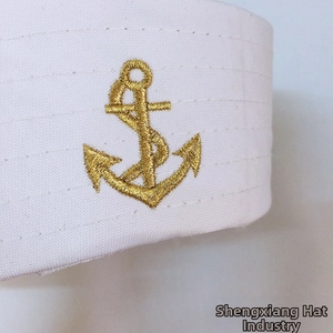Detailed close-up of golden anchor embroidery on a white sailor hat fabric