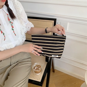 Detailed view of hand-held large canvas striped makeup bag for travel storage