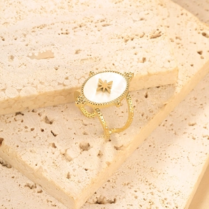 Detailed close-up of gold plated oval ring with white shell inlay and star motif