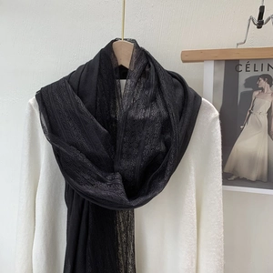 Detailed close-up of a black linen and lace scarf hanging on a wooden hanger with white shirt