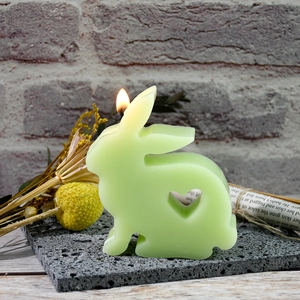 Light green bunny candle with heart cut-out detail on a natural volcanic stone base