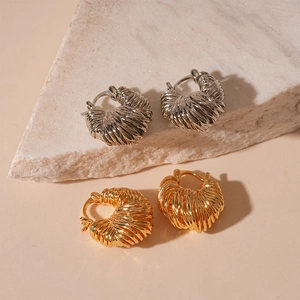 U-shaped gold and silver woven metallic hoop earrings on white marble stone