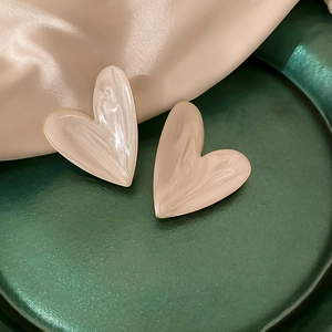 Elegant off-white heart earrings with gold edges on green marble and white silk background