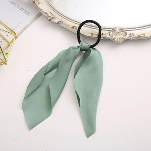 Detail shot of light green silk ribbon hair scrunchie on a decorative vanity table