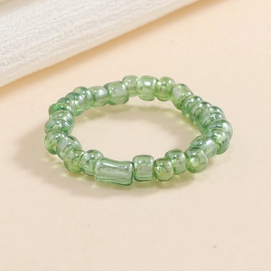 Dettaglio anello elastico con perline verdi tubi di vetro trasparenti e conterie