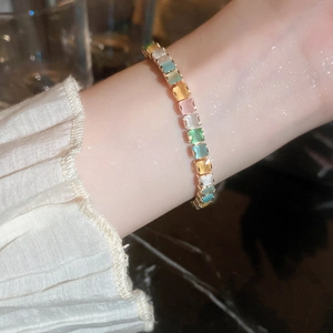 Detail of colorful rectangular zircon tennis bracelet with gold finish on model wrist
