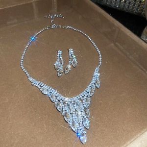 Close-up of sparkling oval tassel necklace and earrings set in a brown jewelry box